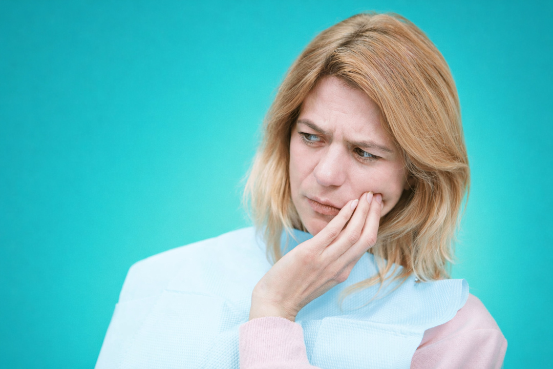 женщина держится за щеку от зубной боли