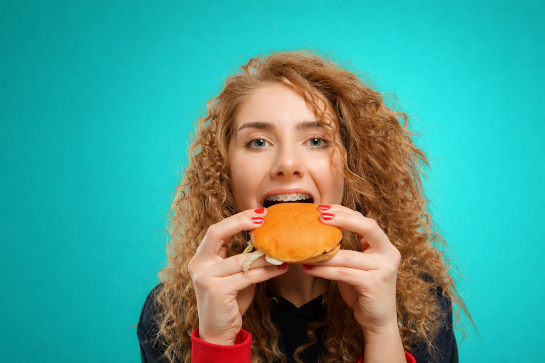 девушка с брекетами ест гамбургер